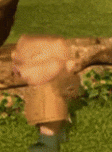 a blurred image of a person standing next to a tree trunk in the grass .