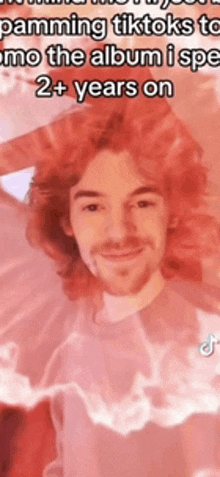 a man with red hair and a beard is smiling in a red background