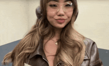 a woman wearing a leather jacket and glasses is smiling .