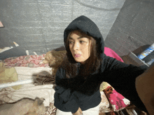 a woman wearing a black hoodie is taking a picture of herself