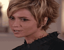 a woman with short blonde hair is wearing a black shirt