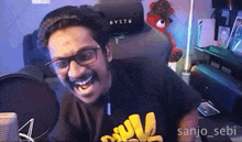 a man with glasses and a mustache is laughing in front of a microphone while wearing a shirt that says skull