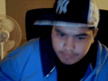 a young man wearing a ny hat and a blue shirt