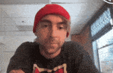 a man wearing a red hat and a black shirt with the letter m on it