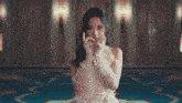 a woman in a white dress is covering her face with her hands .