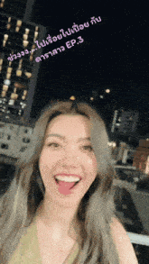 a woman in a green top is smiling in front of a city skyline at night