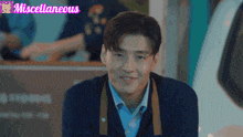 a man is smiling in front of a miscellaneous logo