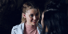 two women are smiling and looking at each other