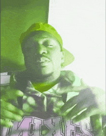 a man wearing a green hat and a hoodie that says ' aoa ' on it