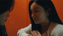 a man and a woman are looking at each other and touching their faces .