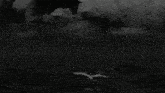 a black and white photo of a full moon in a cloudy night sky