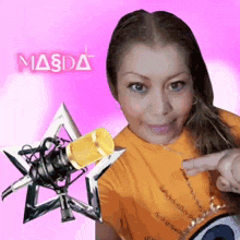 a woman in an orange shirt is pointing at a microphone with the word masda behind her
