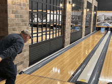 a man is bowling in a bowling alley with a sign on the wall that says " bowling "