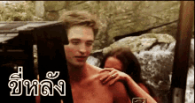 a man without a shirt is being held by a woman in a foreign language .