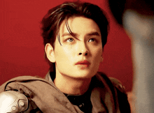 a close up of a young man 's face with a red background behind him