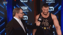 two men are standing in front of a wall that says aew wrestling dynamite