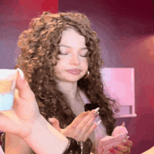a woman with curly hair has her eyes closed while holding a piece of paper