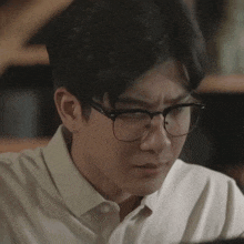 a man wearing glasses and a white shirt is making a face