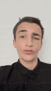 a young man is making a funny face with his eyes closed .