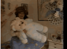 a woman holding a teddy bear in a bedroom