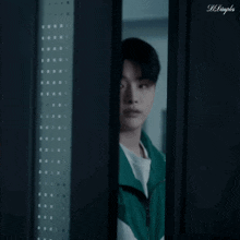 a young man in a green jacket is standing in a doorway