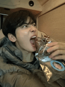 a young man is eating a donut from a plastic bag
