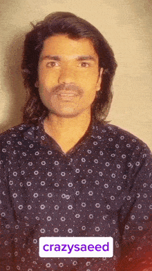a man with long hair and a mustache is wearing a black shirt that says crazysaeed on the bottom