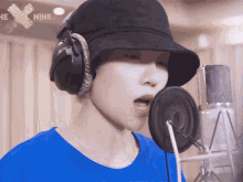 a person wearing headphones and a hat is singing into a microphone with the x nine logo in the background