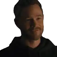 a man with a beard wearing a black hoodie smiles for the camera