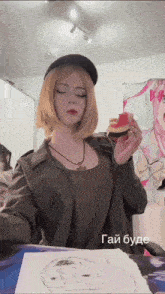 a woman in a hat holds a piece of cake in front of a drawing of a girl