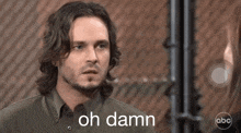 a man in a green shirt says oh damn in front of a chain link fence