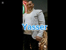 a man in a grey jacket is standing in front of a neon sign that says yasser