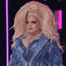 a drag queen is wearing a blue jacket and necklace