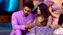 a man is putting a ring on a woman 's finger while they are sitting next to each other .