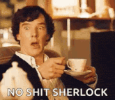 a man is sitting on a couch holding a cup of tea and a saucer and saying no shit sherlock .