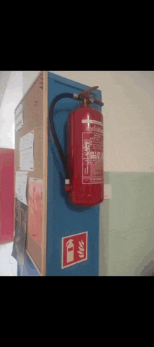 a red fire extinguisher is hanging on a blue wall