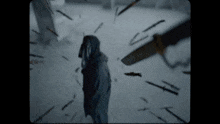 a person in a hooded jacket is surrounded by knives and swords
