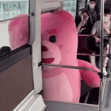 a giant pink teddy bear is sitting on a bus