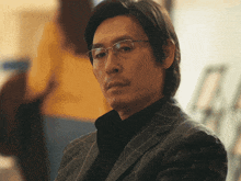 a man wearing glasses and a suit looks serious