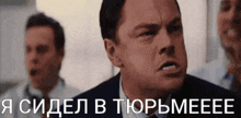 a man in a suit and tie is making a funny face while another man looks on in the background .