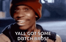 a man wearing a red beanie is smiling and asking , `` yall got some dutch bros ? ''