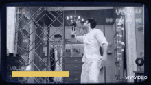 a man in a white shirt is standing in front of a mirrored wall with a sign that says vivavideo