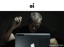 a man is sitting in front of an apple laptop with the words oi above him