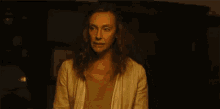 a woman is making a scary face in a dark room with her hands in the air .