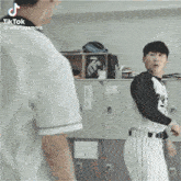 a man in a baseball uniform is standing next to a man in a locker room .