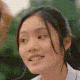 a close up of a girl 's face with a ponytail and a smile on her face .