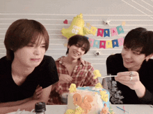 a group of young men are sitting around a birthday cake