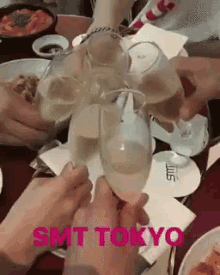 a group of people toasting with wine glasses with smt tokyo written on the bottom of the image