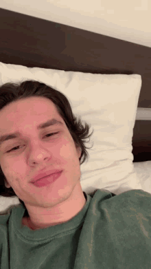 a young man is laying on a bed with a white pillow