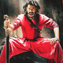 a man in a red shirt holds a sword